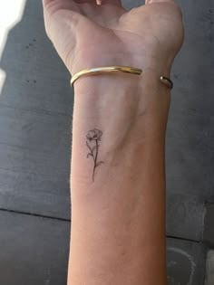 a woman's arm with a small flower tattoo on the left side of her wrist