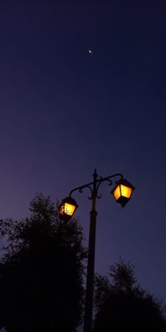 two street lamps with the moon in the background