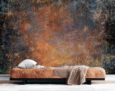 a bed sitting in front of a wall with a painting on it's side