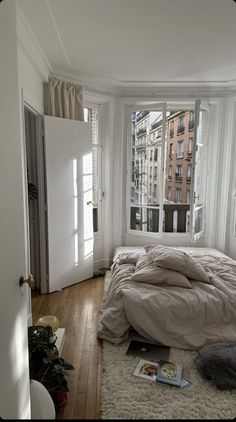 an unmade bed sitting in a bedroom next to a window with lots of windows