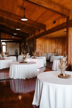 tables with white tablecloths and centerpieces are set up in a large room