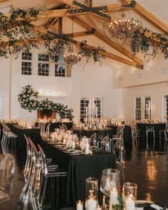 a room filled with lots of tables covered in black table cloths and white candles