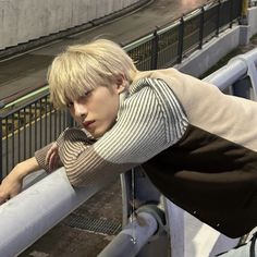 a young man leaning on a rail next to a street