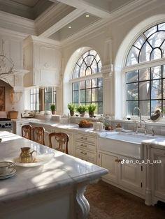 a kitchen filled with lots of white counter top space and large windows above the sink