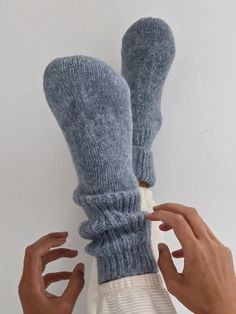 two hands are holding up socks made out of yarn