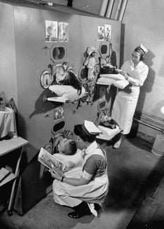 two women in aprons are looking at pictures on the wall and another woman is reading