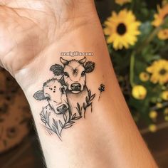 a small cow and calf tattoo on the left wrist, with daisies in the background