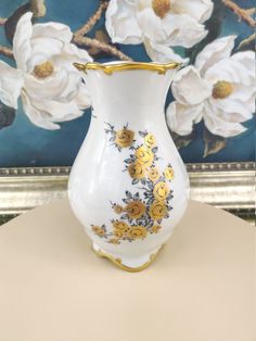 a white vase with yellow flowers painted on it