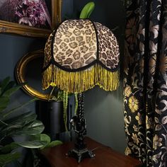 a lamp that is on top of a table next to a mirror and potted plant