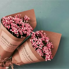 two pink and white flowers wrapped in brown paper with a pair of scissors next to it