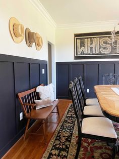 a dining room table and chairs with hats on the wall above them, in front of a blue paneled wall