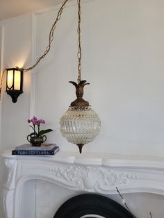 a white fireplace with a light hanging over it