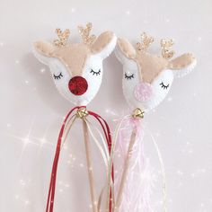 two reindeer head hair clips on top of each other next to a pink and red ribbon