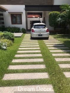 a white car parked in front of a house with grass on the driveway and steps leading up to it