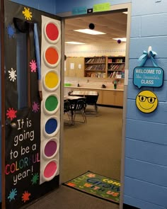 an open door to a classroom with colorful paint and decorations on the doors, in front of a welcome sign that says it is going to be a colorful year