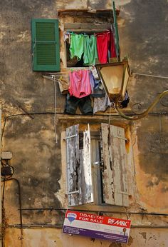 an old building with clothes hanging out to dry on the outside and green shutters