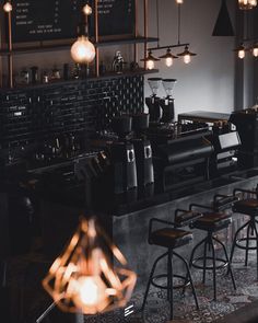 an empty bar with stools and lights hanging from the ceiling