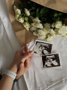 someone is holding the hand of another person near flowers and pictures on a sheet of paper