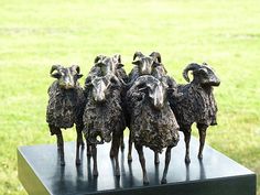 five statues of sheep standing on top of a black stand