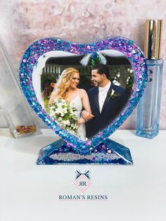 a blue heart shaped photo frame with a bride and groom holding hands in front of it