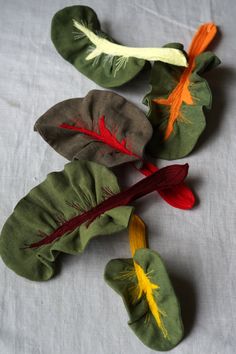 three leaves with red, yellow and green stems on a white tablecloth covered surface