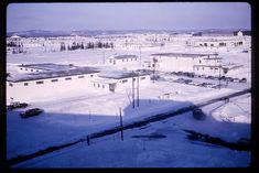 an aerial view of snow covered buildings in the distance and cars parked on the street