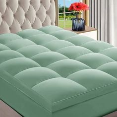 a bed with a tufted headboard and green sheets