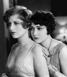 two women in evening dresses posing for the camera, one holding her arm around the other's shoulder