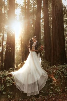 a bride and groom standing in the woods at their wedding day with sun shining through the trees