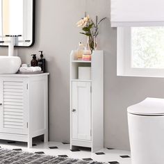 a bathroom with a toilet, sink and cabinet next to a mirror on the wall