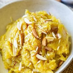 a bowl filled with mashed potatoes topped with almonds and pistachio seeds