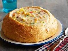 a bowl of soup sits on a plate next to a fork