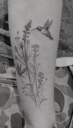 a black and white photo of a hummingbird flying over some wildflowers on the leg