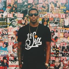 a man standing in front of a wall covered with magazines