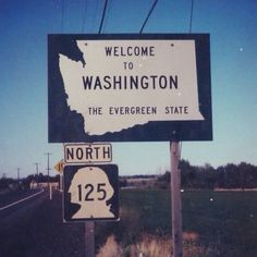 a welcome sign to washington and the evergreen state is posted in front of a highway