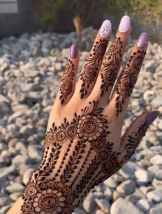 a woman's hand with henna tattoos on it and rocks in the background