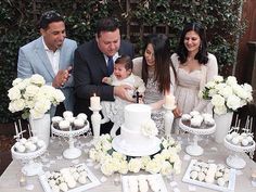 a group of people standing around a table with cake and cupcakes