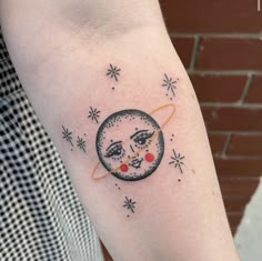 a woman's arm with a tattoo on it that has an image of the moon and stars