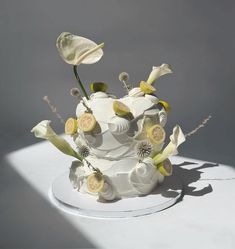 a white cake with flowers and buttons on the top is sitting on a table in front of a gray background