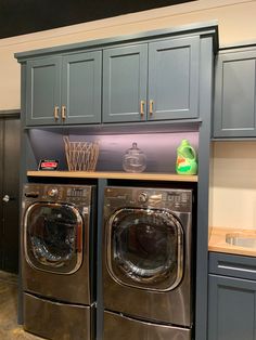 a washer and dryer in a laundry room with blue cabinetry on the walls