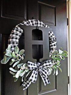 a black and white wreath with the letter h hanging from it's front door