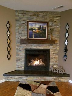 a living room with a fire place in the center and artwork on the wall above it