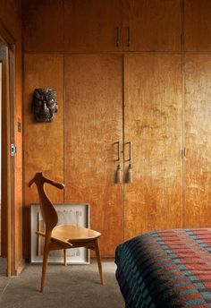 a bedroom with wood paneling and a chair