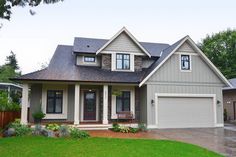 a gray house with white trim and two car garage doors on the front door is surrounded by lush green grass