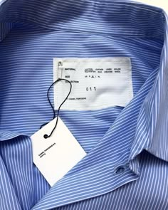 a label on a blue striped shirt that is not buttoned up or untied