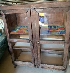 an old wooden cabinet with two glass doors on the front and one door open, in a store