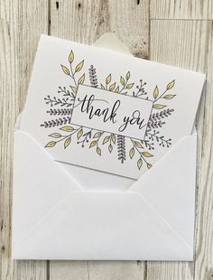 an envelope with the words thank you written in black ink on it, sitting next to a