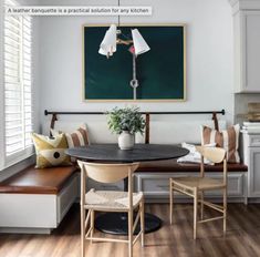 a dining room table with two chairs and a bench in front of a painting on the wall