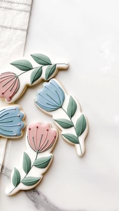 three decorated cookies sitting on top of a white table next to a napkin and fork