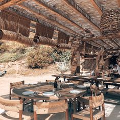 an outdoor dining area with wooden tables and wicker umbrellas on the roof above